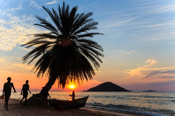 Sunset with palm tree and boat at the beach in africa - obrazy, fototapety, plakaty