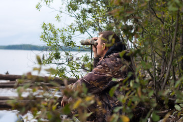 hunter looks through the binoculars at the river
