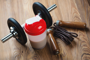 Dumbbell with a protein shake and a jumping rope, studio shot
