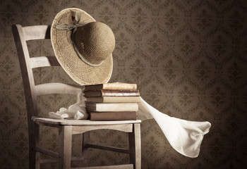 Obraz premium Old books on a chair with straw hat