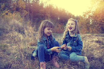 Naklejka na ściany i meble Two young girls amused at autumn sunny day