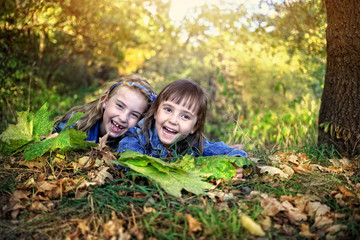 Girls lie under a tree with autumn leaves