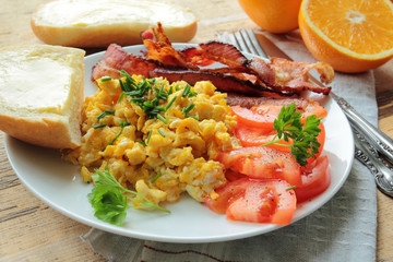 Scrambled eggs with fried bacon and tomatoes for breakfast