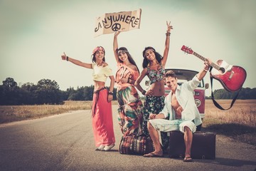 Multi-ethnic hippie hitchhikers with guitar and luggage 