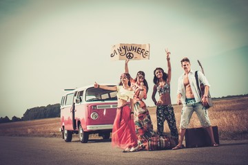 Multi-ethnic hippie hitchhikers with guitar and luggage 
