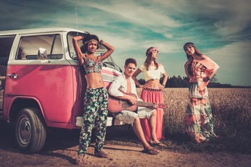 Multi-ethnic hippie friends with guitar on a road trip