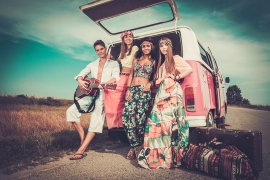 Multi-ethnic hippie friends with guitar on a road trip