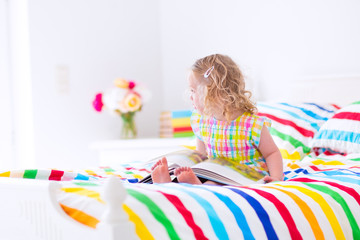 Obraz na płótnie Canvas Little girl reading a book in bed