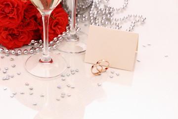 Two golden wedding rings with card, champagne glasses