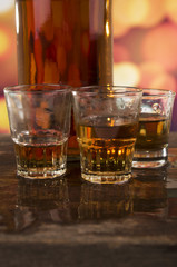 glass of rum whiskey over defocused lights background