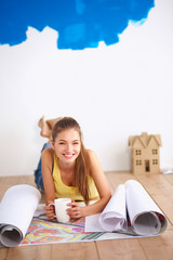 Young woman lying on the floor and looking at blueprint of new