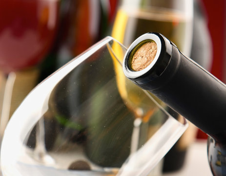 closeup of a bottle with a cork, bottles and glasses on the bac