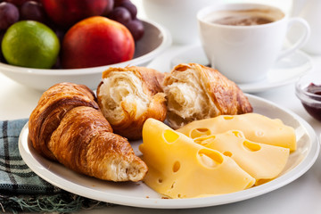 Croissants with cheese, fruits and coffee