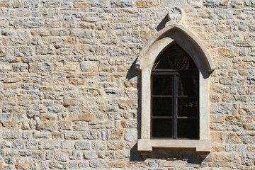 Window with an arch on the old wall in the city of Budva