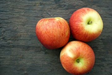 Three red apples on a wooden background