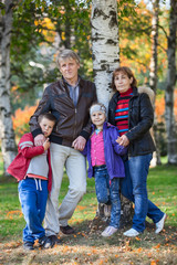 Four people family full length portrait in autumn park