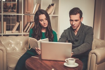 Young couple with laptop and coffee behind table
