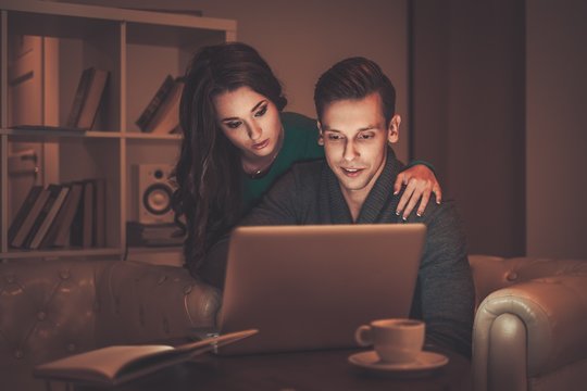 Young Couple With Laptop And Coffee Behind Table