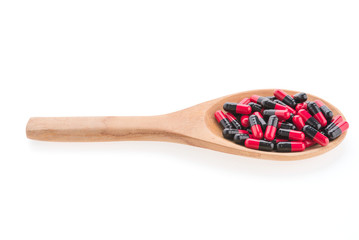 Pills drug on wooden spoon isolated on white background