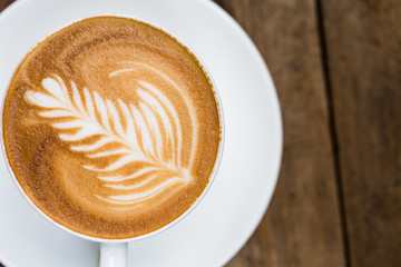 Cup of hot latte art coffee on wooden table