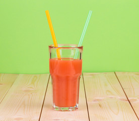 Tomato juice in glass on green background