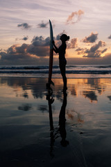 Beautiful young surfer girl in bikini with surfboard on a beach