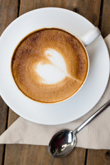 Cup of hot latte art coffee on wooden table