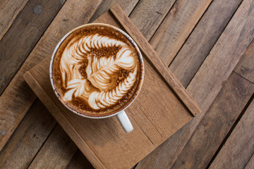 Cup of hot latte art coffee on wooden table