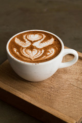 Cup of hot latte art coffee on wooden table