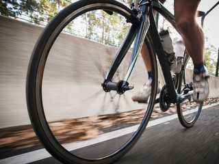 Fototapeta na wymiar Detail of a road bike with a cyclist pedaling on a road.