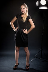 Obraz na płótnie Canvas slim woman in dress posing against black background