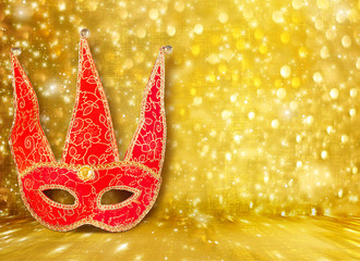 Carnival mask and a red Christmas ball on a golden abstract back