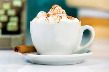 Close up of white cup of coffee with cream, and typewriter.