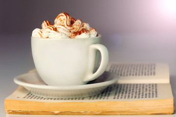 White cup of coffee and cream, on book