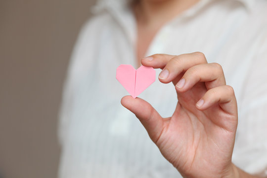 Origami heart in human hand.