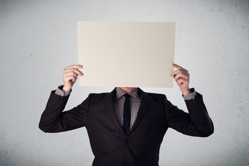 Businessman holding in front of his head a paper with copy space