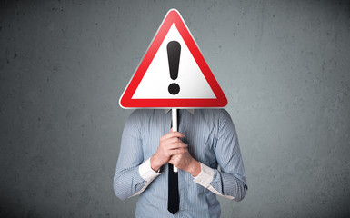 Businessman holding an exclamation road sign
