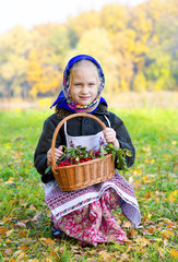 Маленькая девочка на осенней поляне, с корзиной рябины