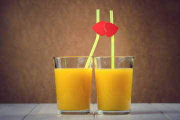 Orange juice glasses with red hearts as a kissing lips
