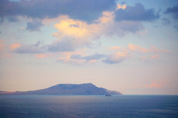 Mountain in sea at sunset