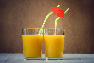 Orange juice glasses with red hearts as a kissing lips