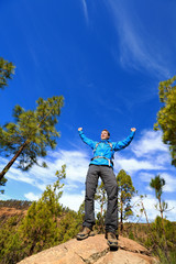 Hiking man reaching summit top cheering in forest