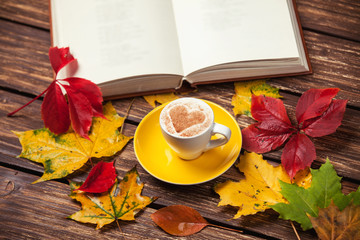 Naklejka na ściany i meble Autumn leafs, book and coffee cup on wooden table.