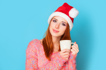 Redhead girl with cup on blue background.