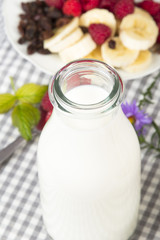 bottle of fresh milk and fruit: banana, raspberries and raisins