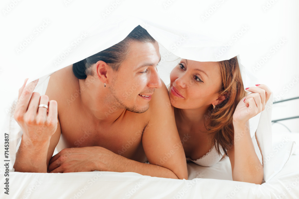 Wall mural  guy and woman  together under sheet on bed