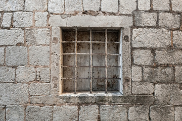 Fototapeta na wymiar Locked ancient stone prison wall with metal window bars