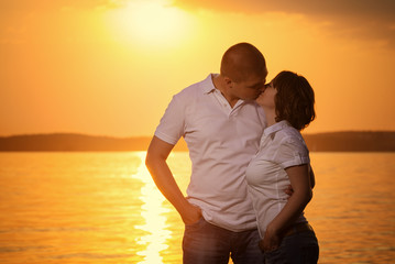 Fototapeta premium Young romantic couple look to each other during sunset on the be
