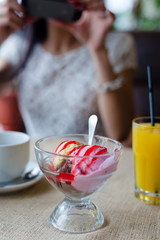 closeup image on ice cream in coffee shop or restaurant with female girl having fun holding mobile device taking selfie or selfy picture of herself