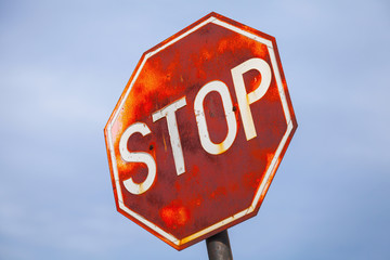 Old stop road sign above blue cloudy sky